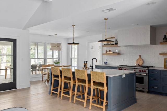 kitchen with visible vents, decorative backsplash, designer stove, light wood-style floors, and open shelves