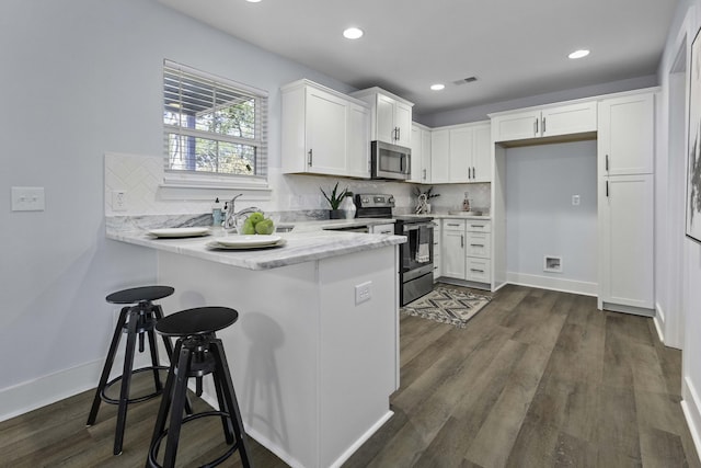 kitchen with visible vents, white cabinetry, stainless steel appliances, a peninsula, and dark wood-style flooring