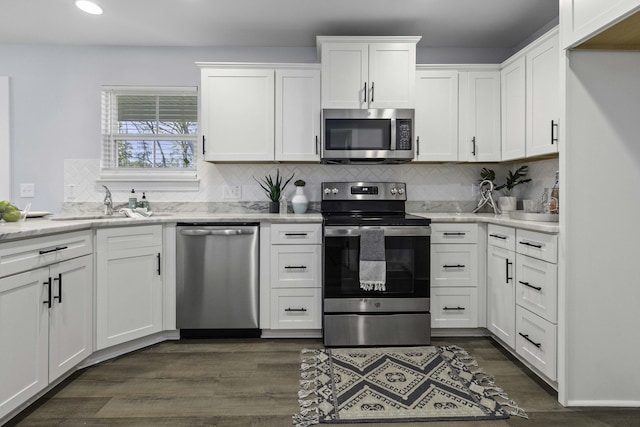 kitchen featuring backsplash, dark wood-type flooring, appliances with stainless steel finishes, white cabinets, and a sink