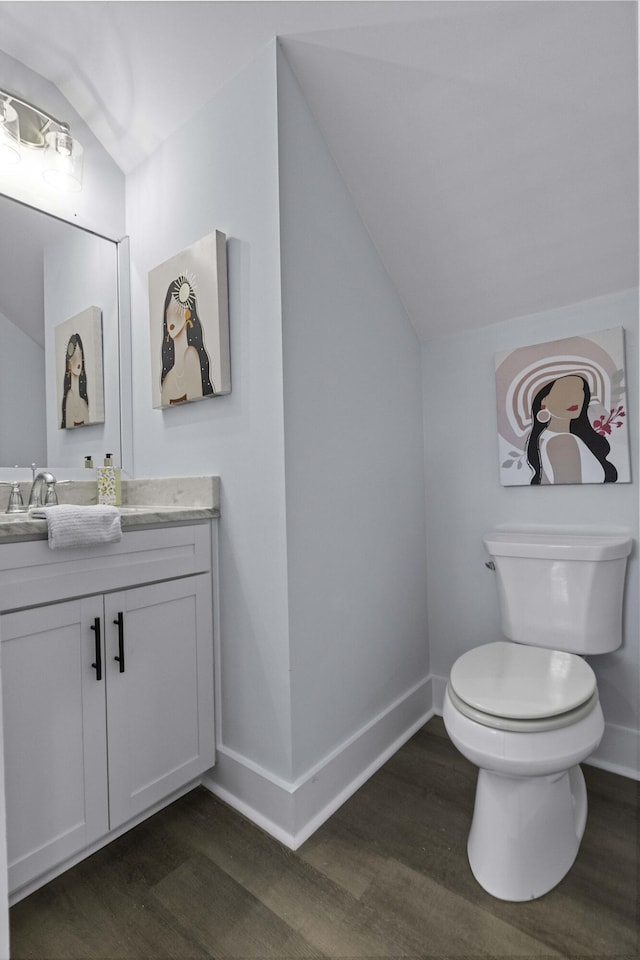 bathroom featuring baseboards, toilet, wood finished floors, and vaulted ceiling