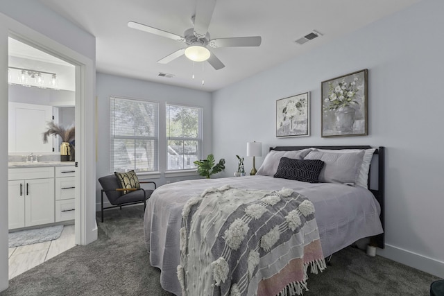 bedroom with visible vents, light colored carpet, ensuite bath, and a sink