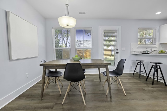 dining space with visible vents, a healthy amount of sunlight, and dark wood-type flooring