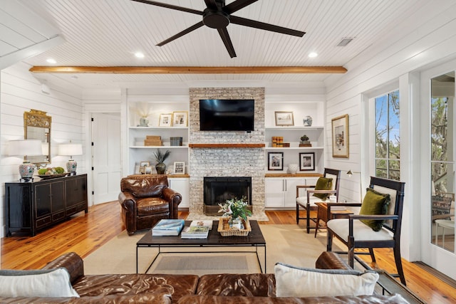 1809 Rushland Grove Ln, Johns Island, SC 29455 - living area with light wood-type flooring, ceiling fan, a wood ceiling with exposed beams, a stone fireplace, and wooden walls