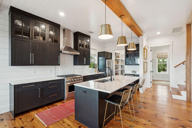 1809 Rushland Grove Ln, Johns Island, SC 29455 - kitchen with high end stainless steel range oven, wall chimney exhaust hood, a breakfast bar area, light wood-style floors, and decorative light fixtures