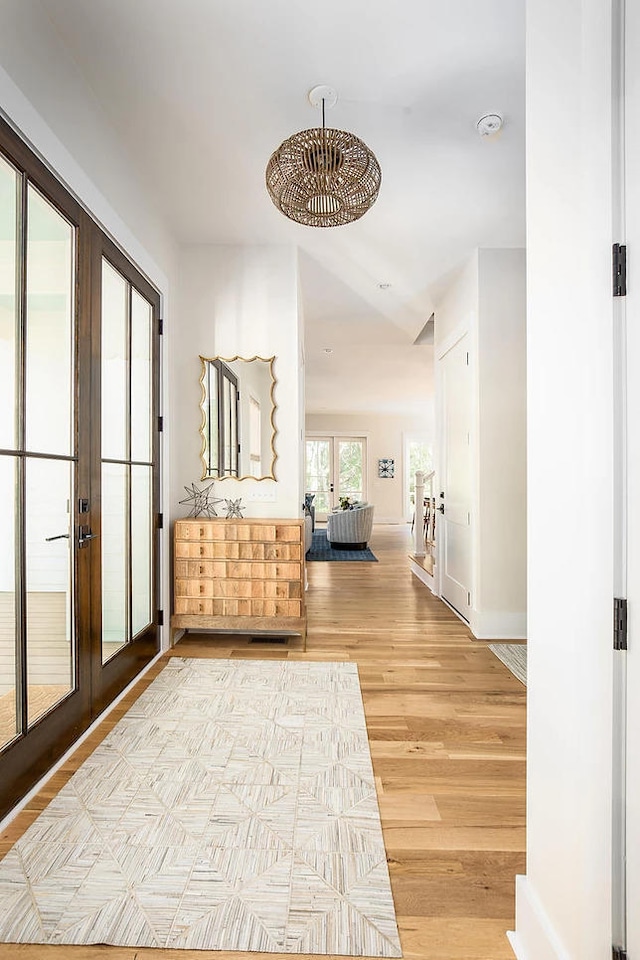 corridor with french doors and light hardwood / wood-style floors