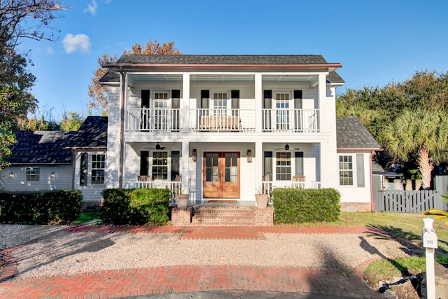 view of front of property with a porch, a balcony, and french doors