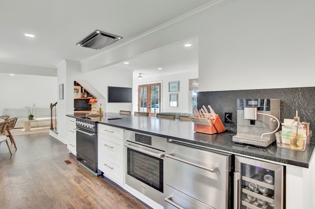 kitchen with white cabinetry, stainless steel appliances, dark wood-type flooring, wine cooler, and crown molding