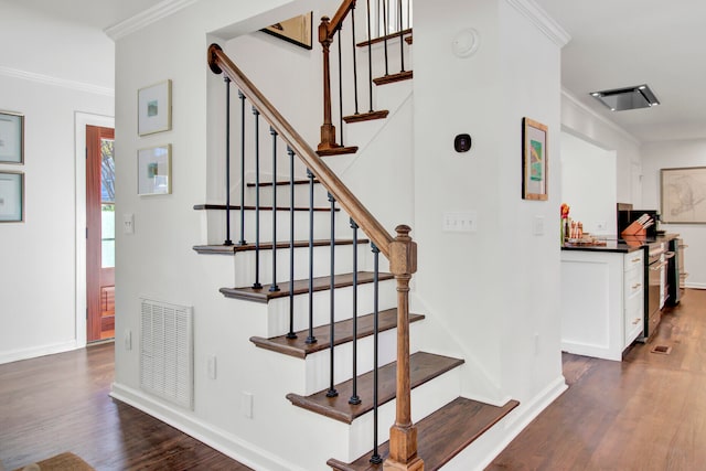 stairs featuring crown molding and hardwood / wood-style floors