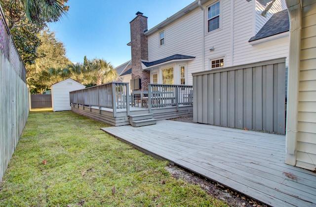 back of house with a lawn, a wooden deck, and a storage shed