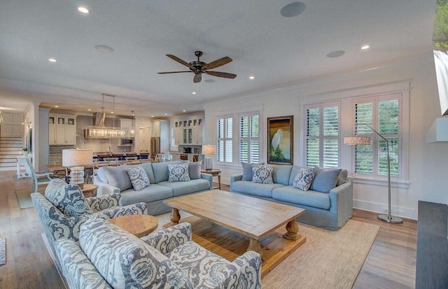 living room featuring crown molding, ceiling fan, and light hardwood / wood-style flooring