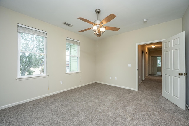 empty room with a ceiling fan, visible vents, light carpet, and baseboards