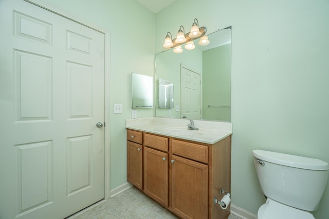 bathroom featuring toilet, baseboards, and vanity