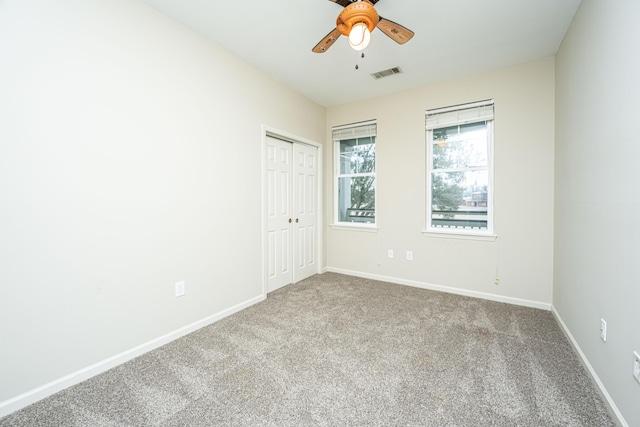 unfurnished bedroom with a ceiling fan, visible vents, baseboards, a closet, and carpet