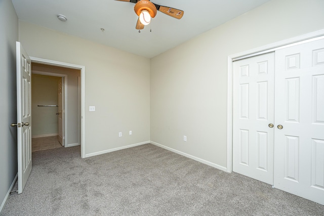 unfurnished bedroom with a closet, light colored carpet, ceiling fan, and baseboards