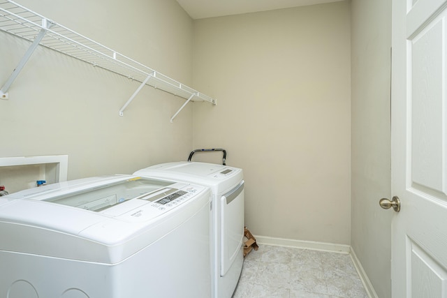 clothes washing area featuring laundry area, baseboards, and separate washer and dryer