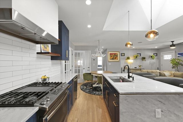 2605 Mona Ave, Charleston, SC 29414 - kitchen with stainless steel gas range oven, a sink, wall chimney range hood, blue cabinetry, and light wood-style floors