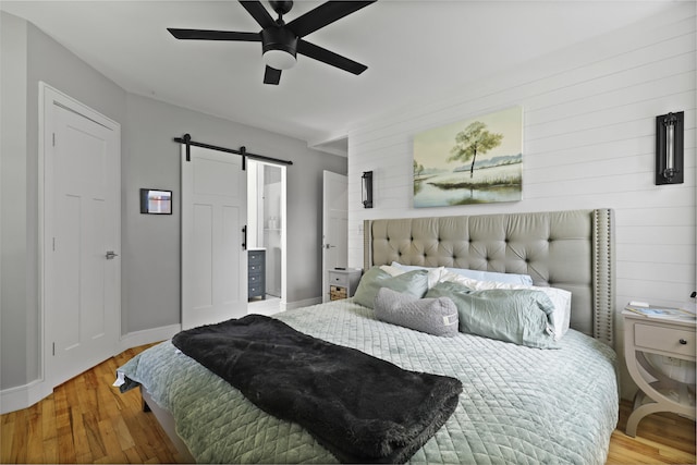 2605 Mona Ave, Charleston, SC 29414 - bedroom featuring a barn door, wood finished floors, baseboards, wood walls, and a ceiling fan