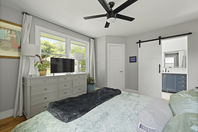2605 Mona Ave, Charleston, SC 29414 - bedroom featuring a barn door, baseboards, wood finished floors, a ceiling fan, and ensuite bath