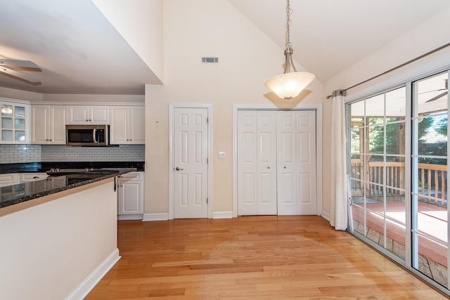 kitchen featuring white cabinetry, decorative backsplash, hanging light fixtures, and light hardwood / wood-style flooring