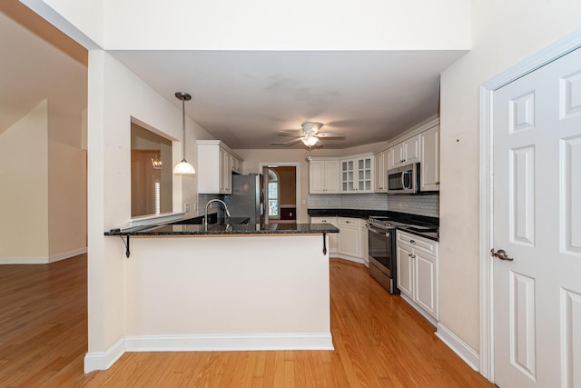 kitchen featuring stainless steel appliances, kitchen peninsula, hanging light fixtures, and white cabinets