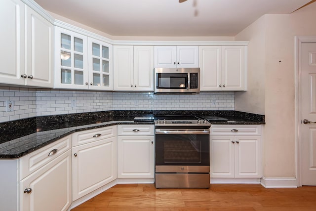 kitchen featuring white cabinetry, stainless steel appliances, light hardwood / wood-style floors, and dark stone counters