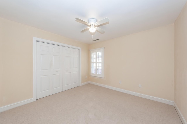 unfurnished bedroom featuring ceiling fan, a closet, and light carpet