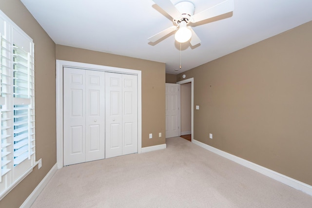 unfurnished bedroom with ceiling fan, a closet, and light carpet