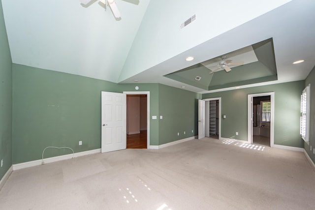 unfurnished bedroom with a raised ceiling, ceiling fan, light colored carpet, and high vaulted ceiling