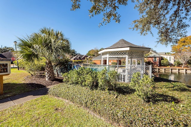 rear view of property with a gazebo, a water view, and a lawn