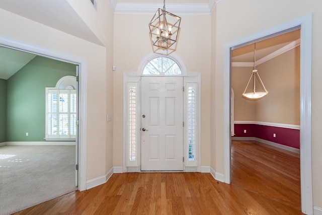 entrance foyer with crown molding, a healthy amount of sunlight, a chandelier, and light wood-type flooring