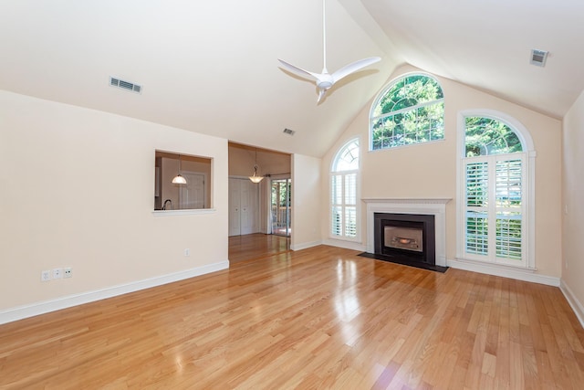 unfurnished living room featuring wood-type flooring, high vaulted ceiling, ceiling fan, and plenty of natural light