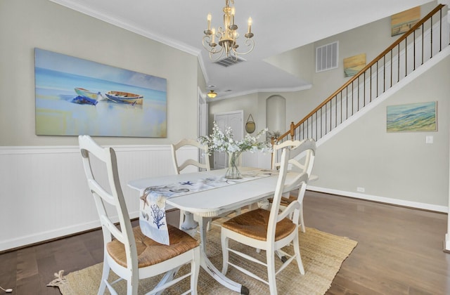 dining space featuring a chandelier, wood finished floors, visible vents, and crown molding