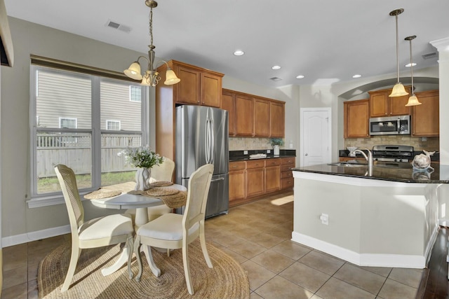 kitchen with brown cabinetry, light tile patterned floors, visible vents, and stainless steel appliances