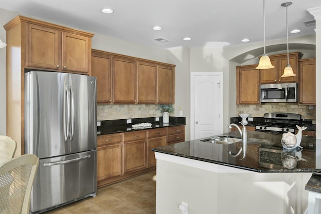 kitchen with stainless steel appliances, brown cabinets, a sink, and hanging light fixtures