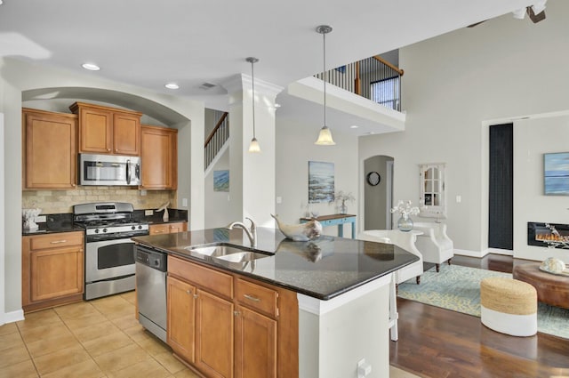 kitchen with decorative light fixtures, stainless steel appliances, tasteful backsplash, open floor plan, and a sink