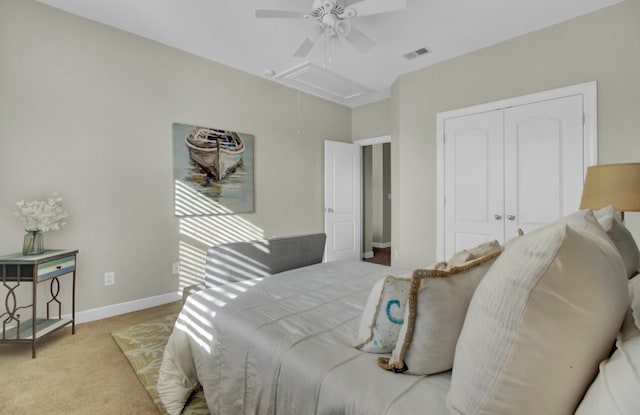 carpeted bedroom with visible vents, a ceiling fan, baseboards, a closet, and attic access