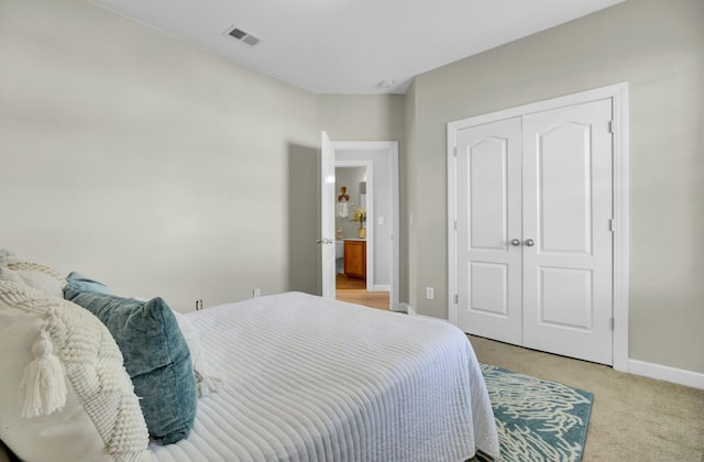 bedroom with a closet, light colored carpet, visible vents, and baseboards