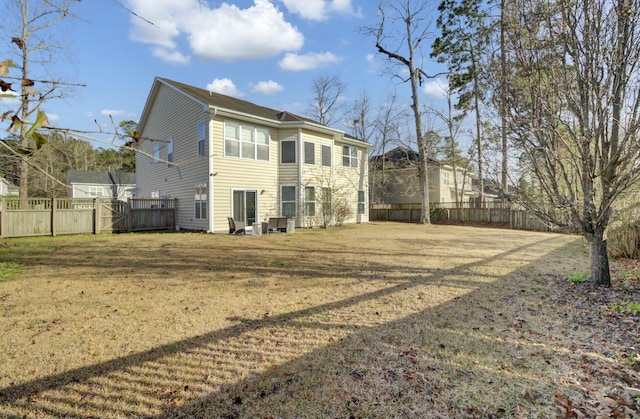 rear view of property featuring fence and a yard