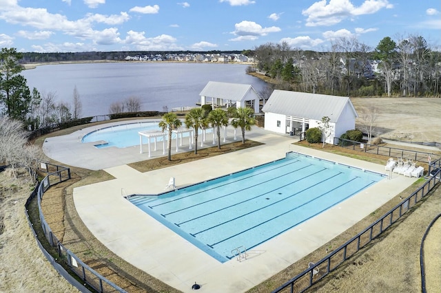 community pool with a water view, a patio area, and fence