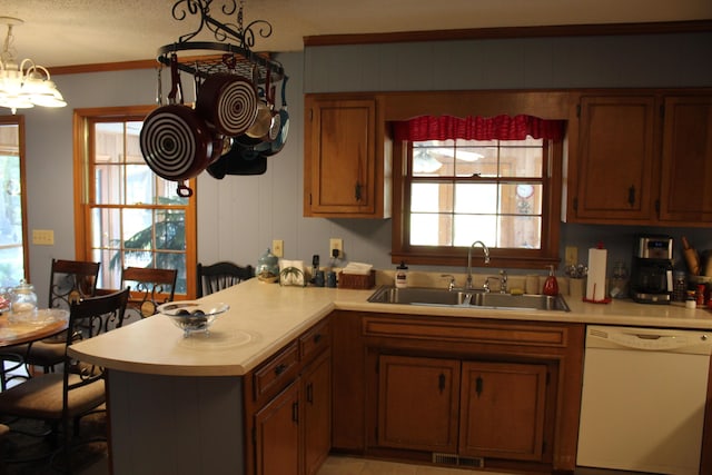 kitchen with light countertops, visible vents, white dishwasher, a sink, and a peninsula