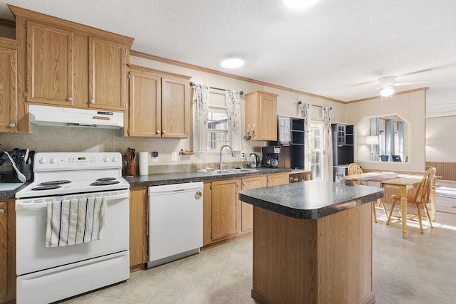 kitchen featuring ornamental molding, white appliances, dark countertops, under cabinet range hood, and a sink