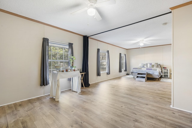 unfurnished bedroom featuring a textured ceiling, ornamental molding, a ceiling fan, and wood finished floors