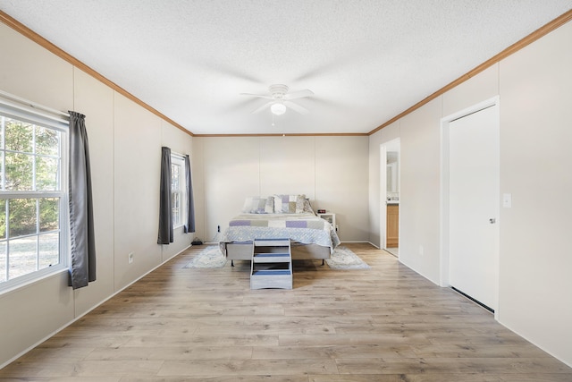bedroom with ornamental molding, a ceiling fan, light wood-style floors, a textured ceiling, and connected bathroom