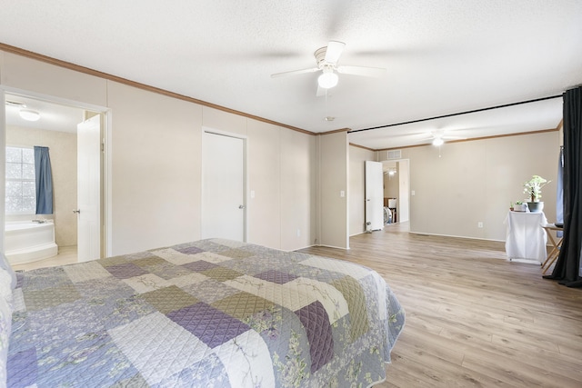 bedroom with light wood-style flooring, a textured ceiling, crown molding, a ceiling fan, and ensuite bathroom