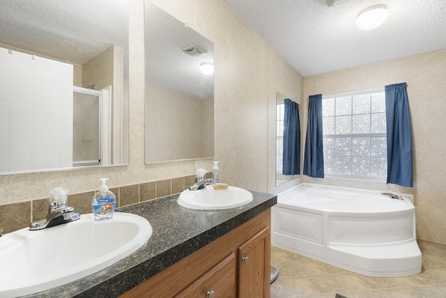 full bath with a sink, a bath, a stall shower, and a textured ceiling
