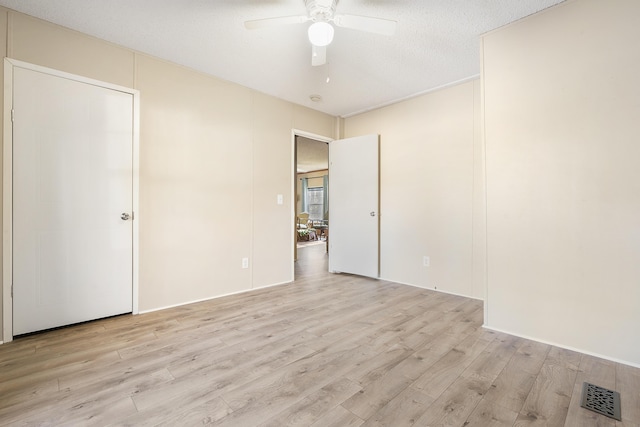 unfurnished bedroom featuring light wood-style floors, a ceiling fan, visible vents, and a textured ceiling