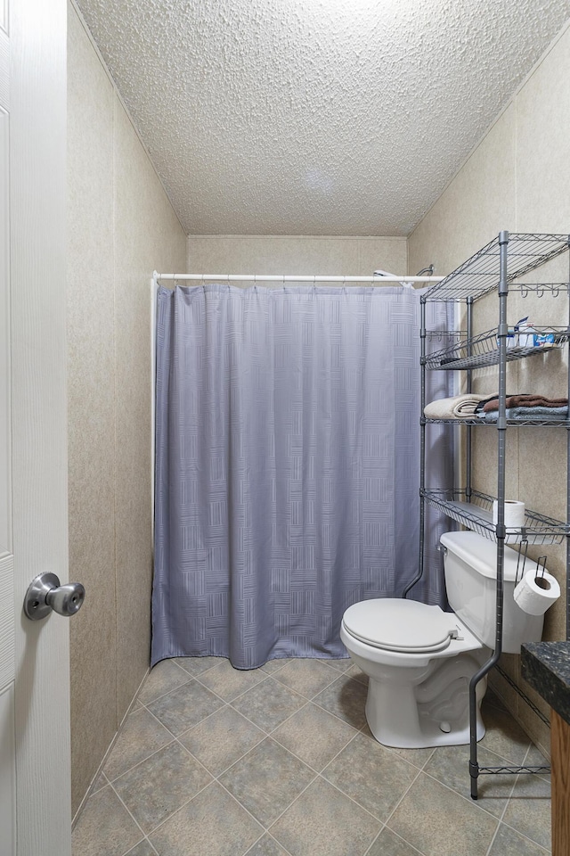 bathroom featuring tile patterned floors, toilet, a shower with shower curtain, and a textured ceiling