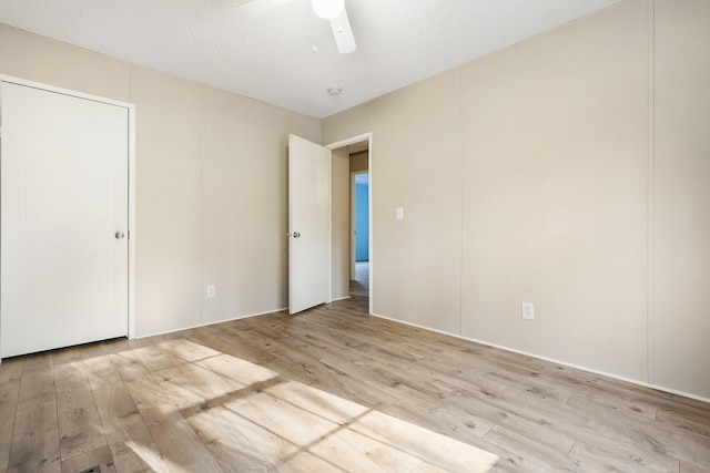 unfurnished bedroom with light wood-style flooring, ceiling fan, and a textured ceiling