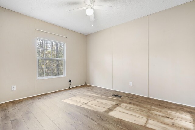 empty room featuring visible vents, a ceiling fan, wood finished floors, and a textured ceiling