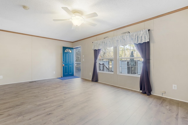 spare room featuring crown molding, ceiling fan, wood finished floors, and a textured ceiling